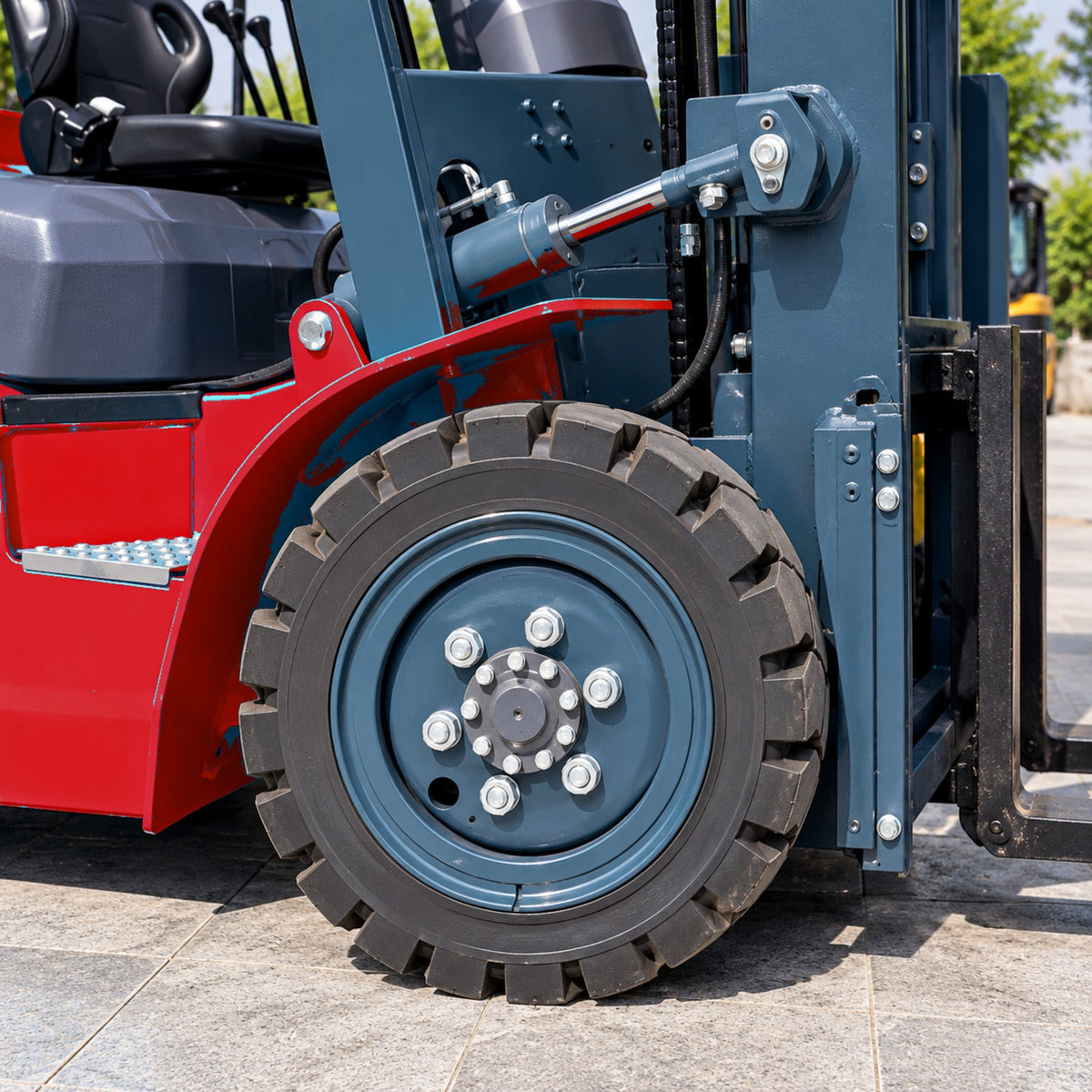 Chariot élévateur électrique 3,5 tonnes CPD-35 – coloris rouge – détail de la roue avant et du vérin d'inclinaison